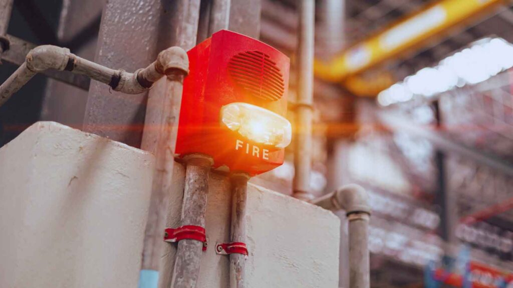 Industrial fire alarm with strobe light flashing during a test – common fire alarm correction issues and their fixes. 