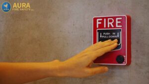 Hand pushing fire alarm pull station during inspection – common fire alarm correction issues and how they are addressed.