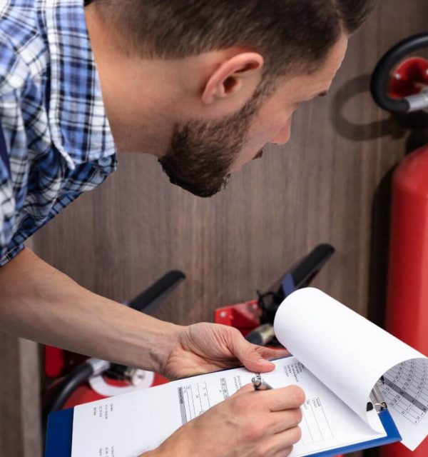 A meticulous technician performing a quarterly fire sprinkler inspection, carefully reviewing the checklist to ensure compliance and safety in a workplace environment.