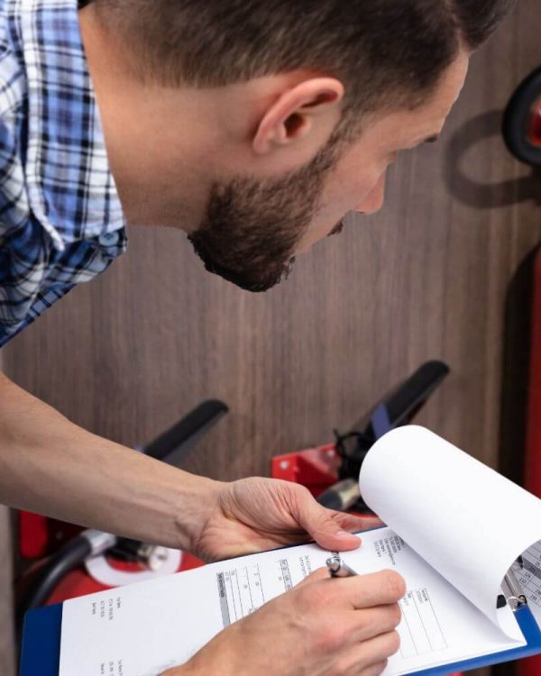 A meticulous technician performing a quarterly fire sprinkler inspection, carefully reviewing the checklist to ensure compliance and safety in a workplace environment.